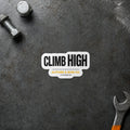 Climb High black and gold sticker displayed on a steel workbench